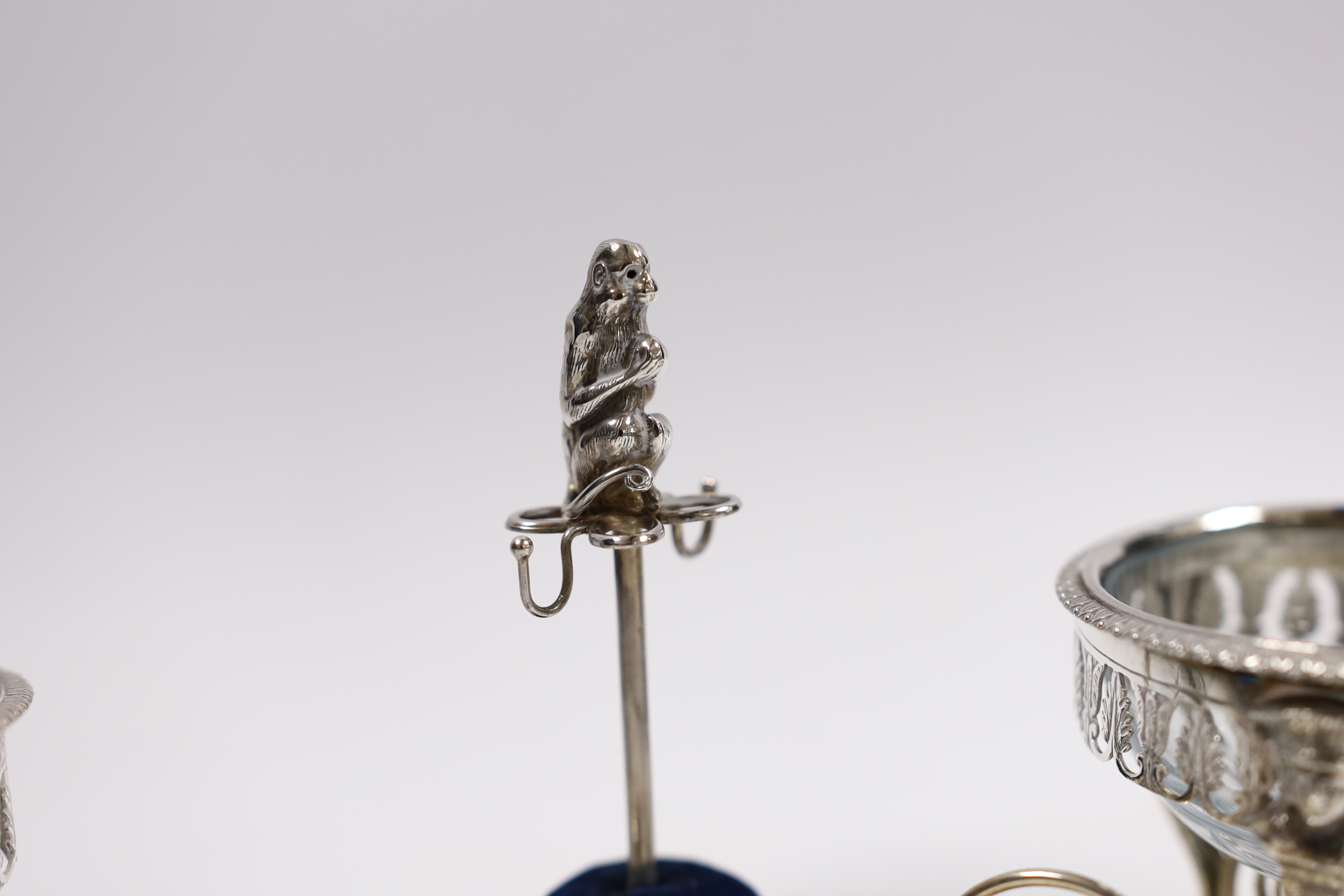 A pair of continental white metal mounted glass cauldron salts, with one associated spoon, an Edwardian silver mounted ring tree/hat pin stand, with monkey surmount, Birmingham, 1909, 10.2cm, a silver cheroot case and a